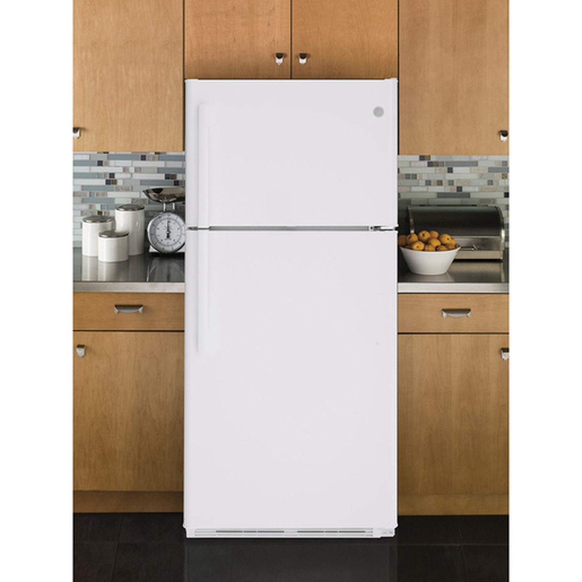 White GE top-freezer refrigerator installed between wood kitchen cabinets