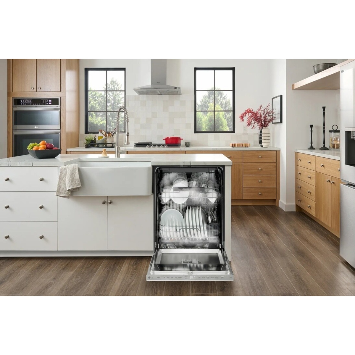 Open LG dishwasher in a bright kitchen with racks loaded with plates, bowls, and glasses