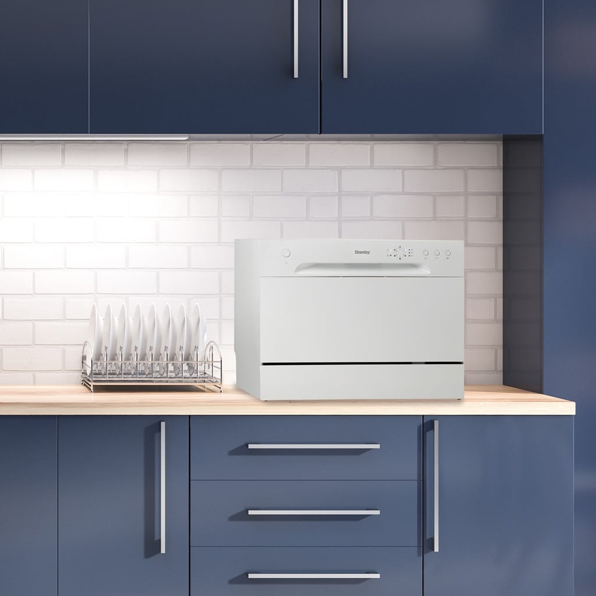 Danby white countertop dishwasher placed on a kitchen counter under upper cabinets
