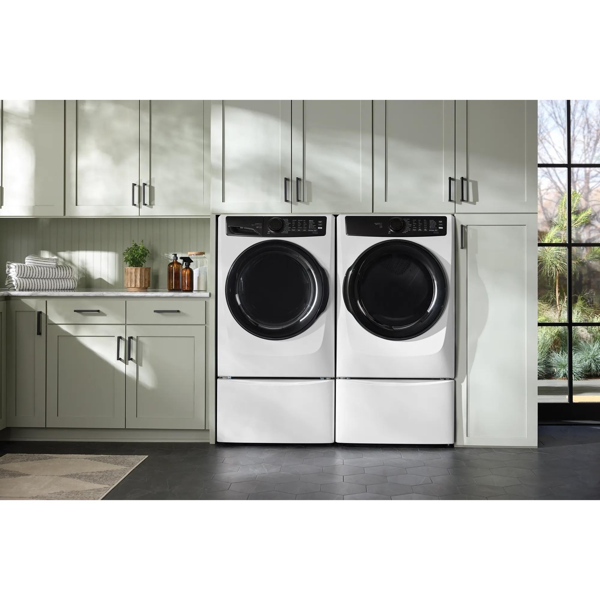 Electrolux front load washer and matching dryer installed side by side on pedestals in a finished laundry room