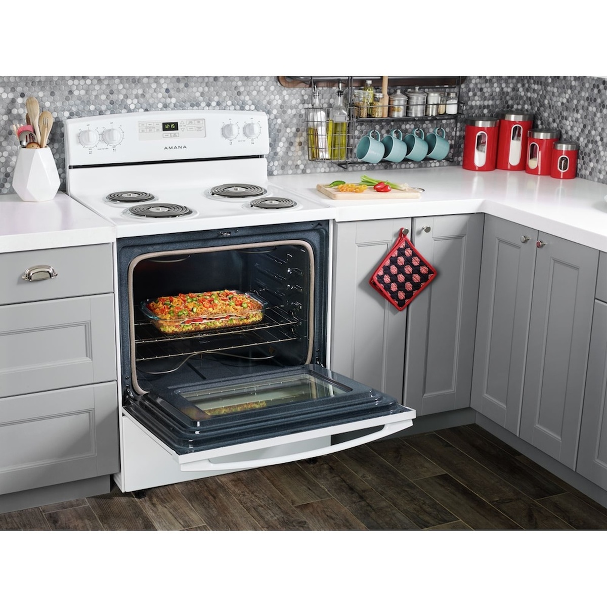 White Amana electric freestanding range installed in a kitchen with the oven door open and food baking on the rack