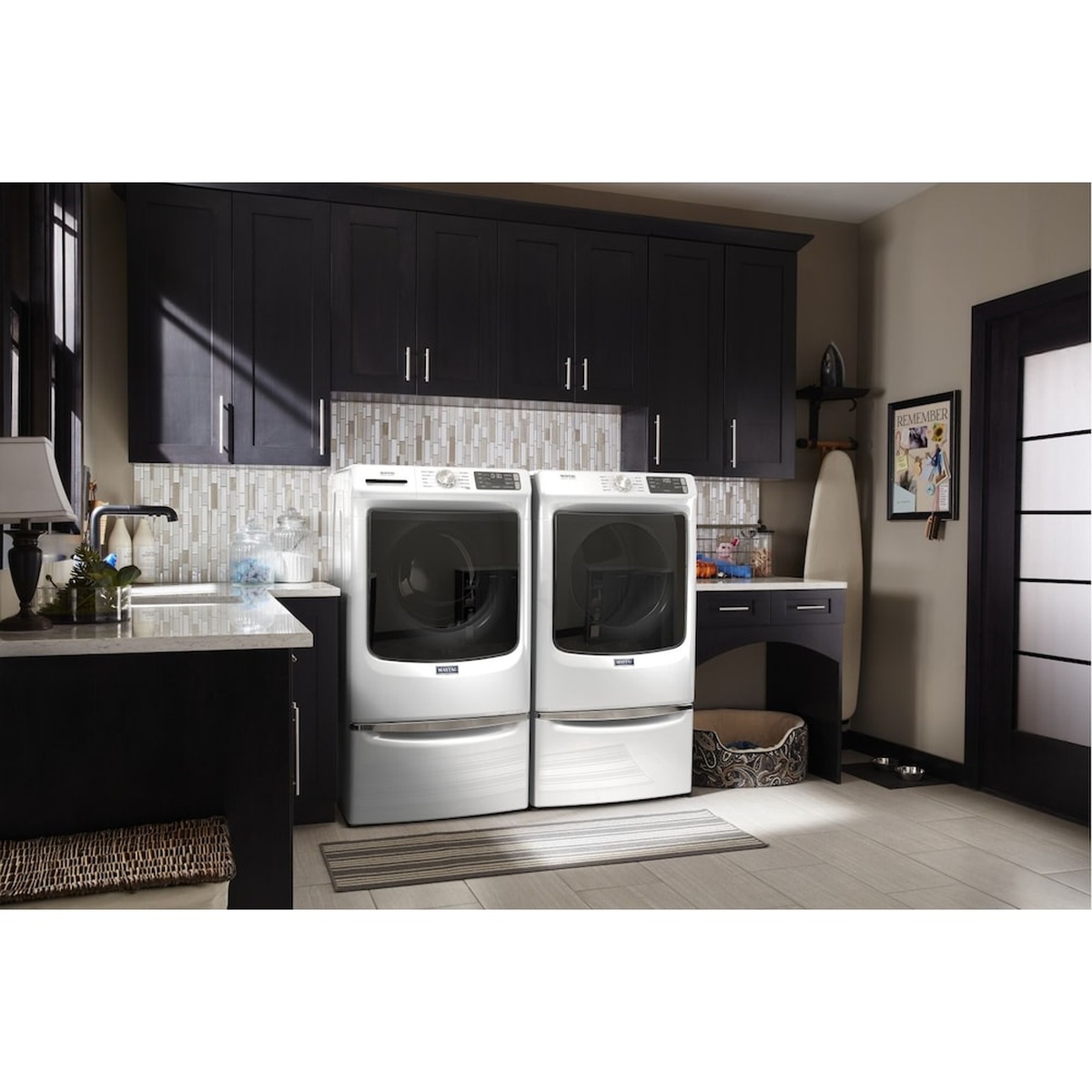 Maytag washer and dryer pair installed side by side in a finished laundry room with cabinetry