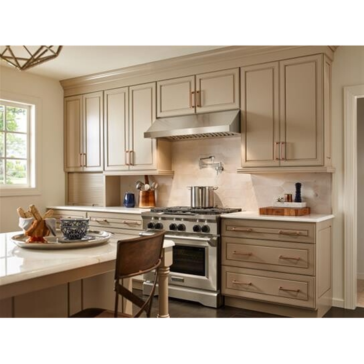 Stainless under-cabinet range hood installed between upper cabinets above a professional-style range in a kitchen