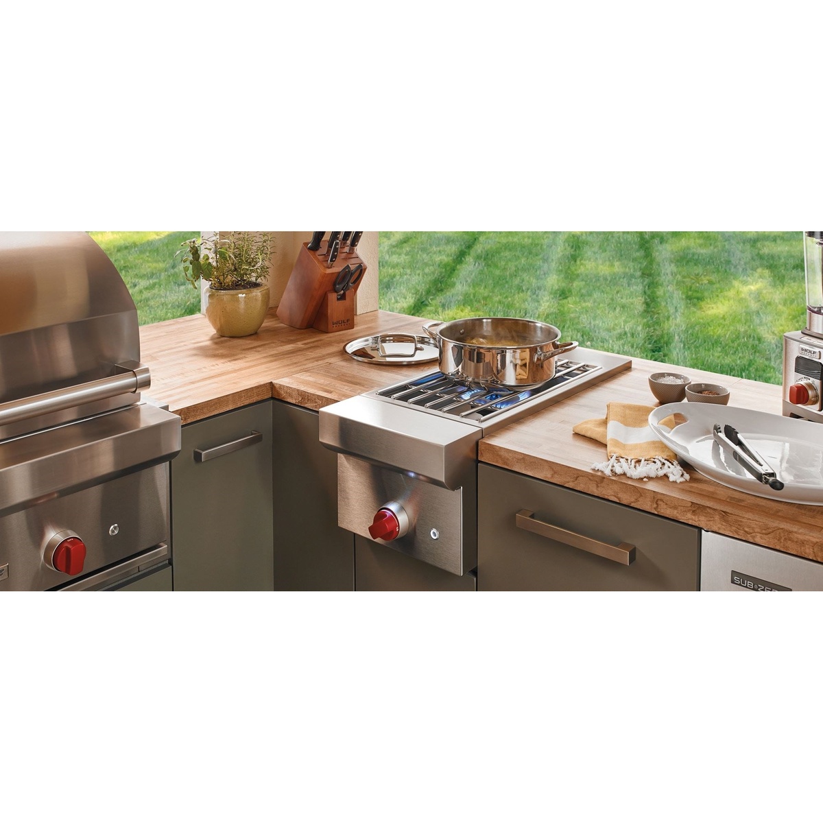 Built-in outdoor burner module installed in a countertop with a pot cooking and a red control knob