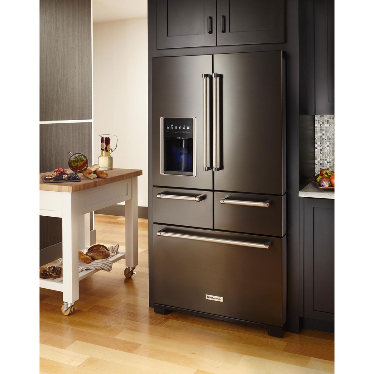 KitchenAid black stainless steel French door refrigerator installed in a modern kitchen with an exterior dispenser and long metal handles