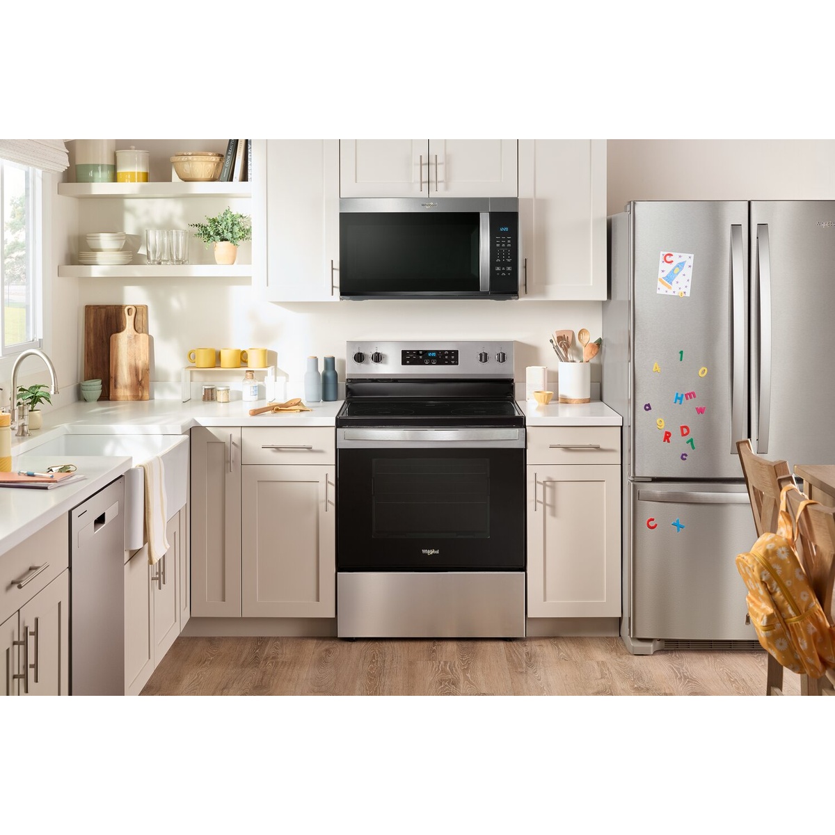 Whirlpool over-the-range microwave installed above a kitchen range within white cabinetry